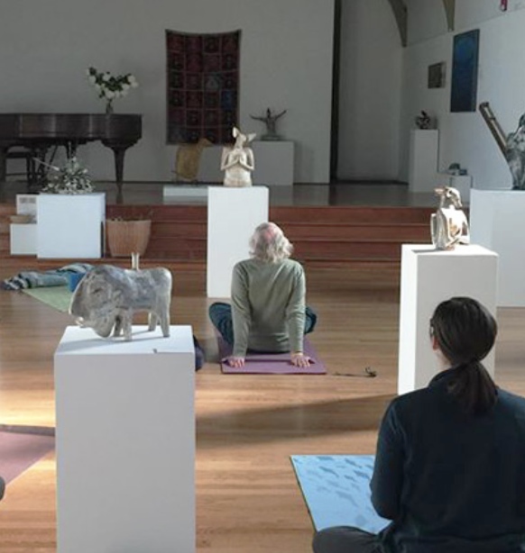 people practicing yoga amongst artwork in the gallery